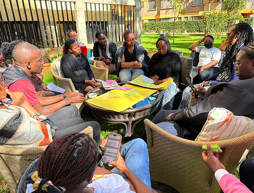 A NairoBits team in discussion around a table of papers